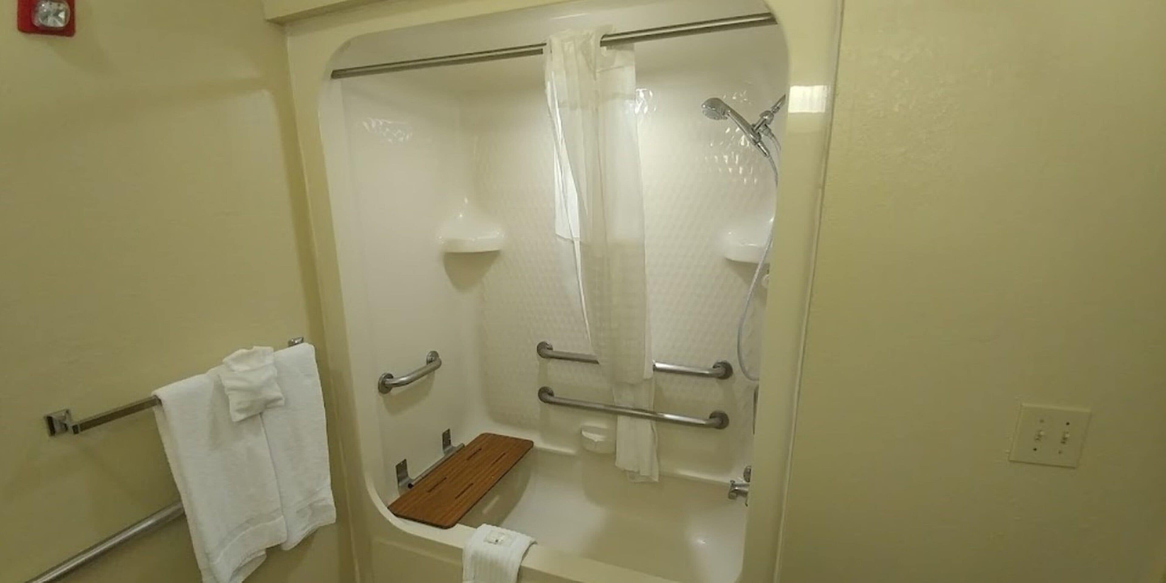 A bathroom with a bathtub, a shower, and a wooden shelf.