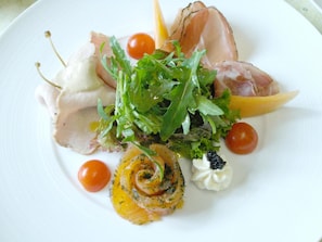 Un plato con diferentes alimentos, como verduras, tomates y una rebanada de carne.