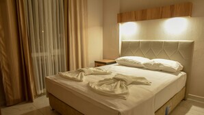 A neatly made bed with a headboard, a bedside table, and a curtain. - Irbec Apart & Bungalow (Demre)