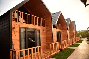 Une rangée de chalets en bois dotés de balcons, de grandes portes-fenêtres coulissantes et d’une terrasse dallée.
