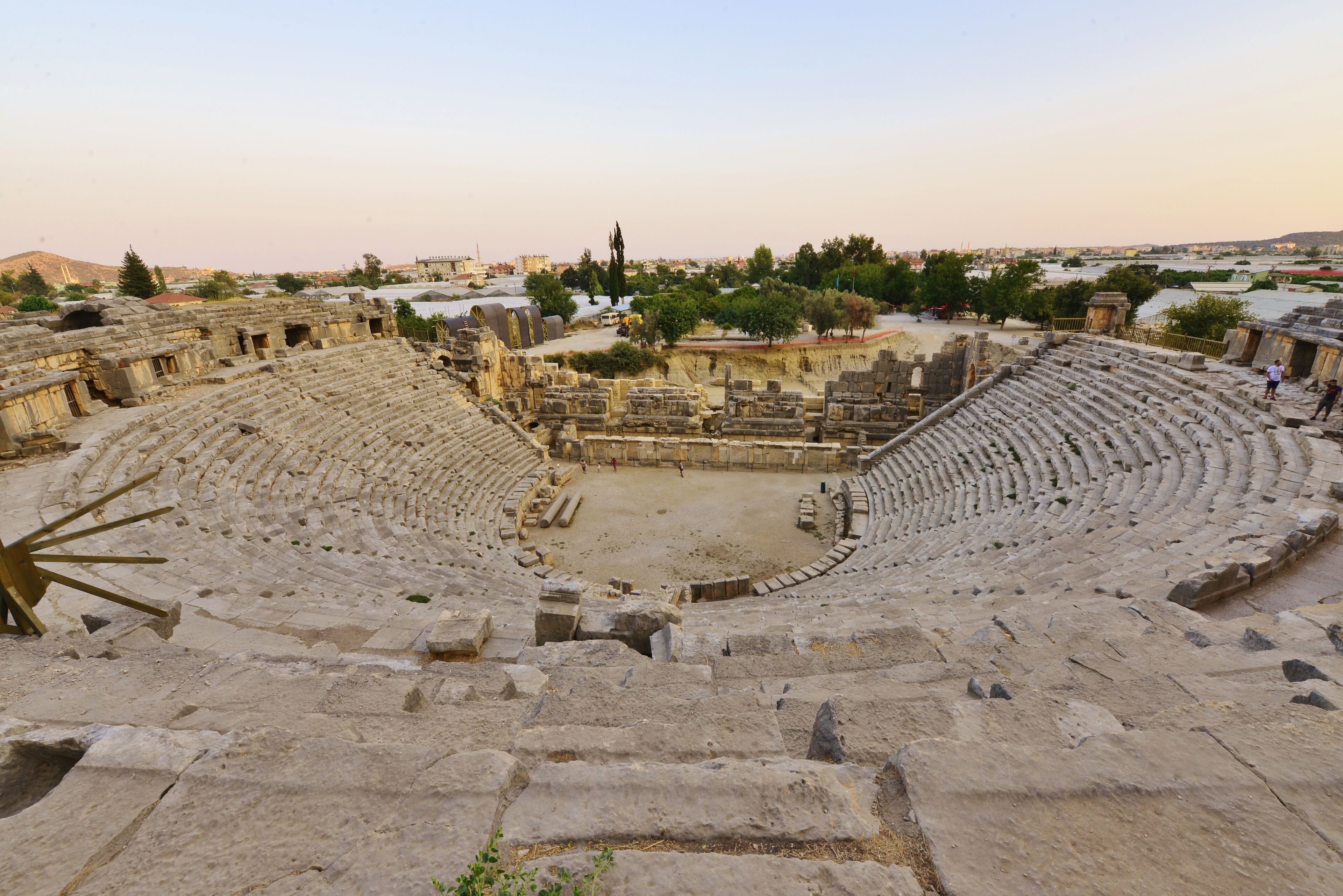An ancient amphitheater with tiered seating and a central stage area.