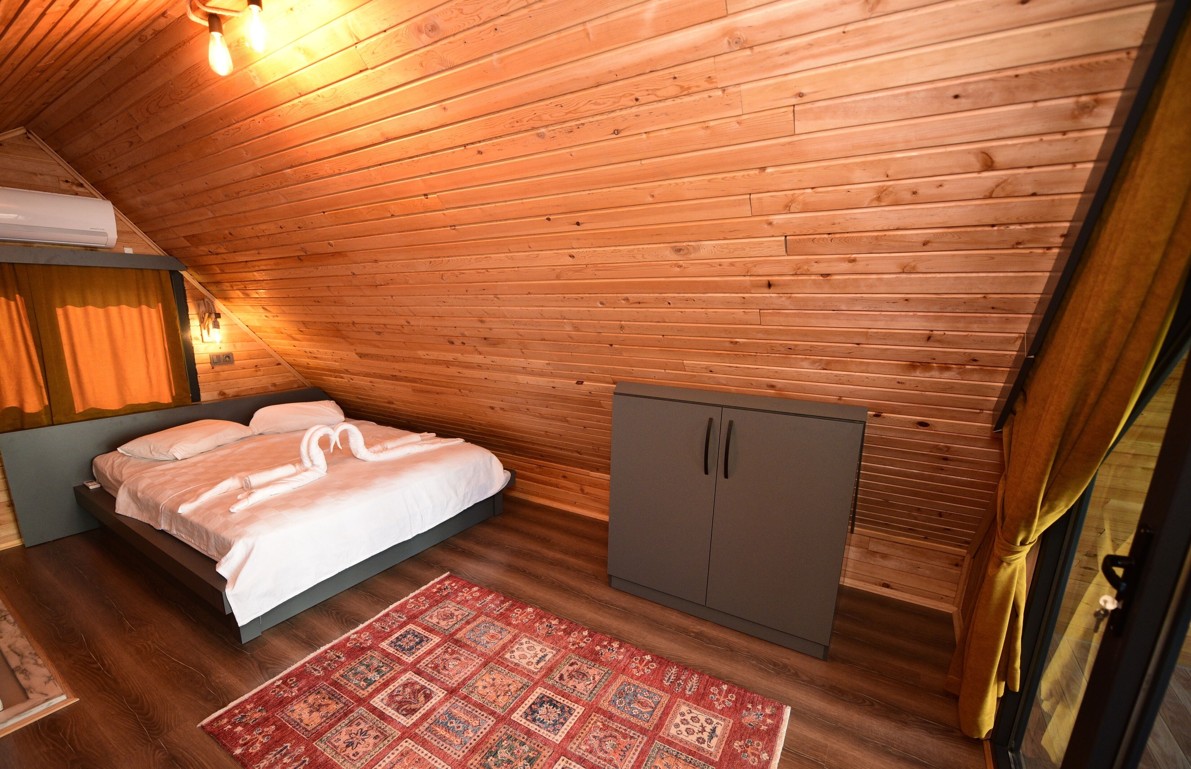 Ein Zimmer mit Holzwänden, einem Bett, einem Schrank und einem gemusterten Teppich.