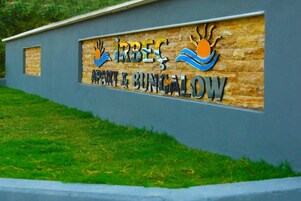 Letrero de 'IRBEC Apartment & Bungalow' con un logotipo que presenta un sol estilizado y olas.