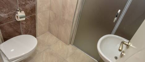 A bathroom with a toilet, sink, and shower.