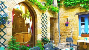 Un espacio de descanso al aire libre rústico, con paredes de piedra, puertas de madera y plantas en macetas.