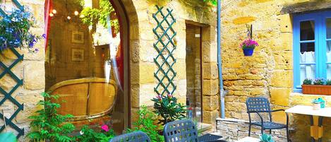 A rustic outdoor seating area with stone walls, wooden doors, and potted plants.