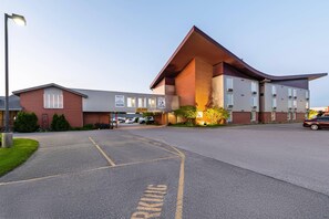 A modern building with a unique triangular roof, a parking lot, and a sign welcoming visitors. - Rodeway Inn Festival (Stratford)