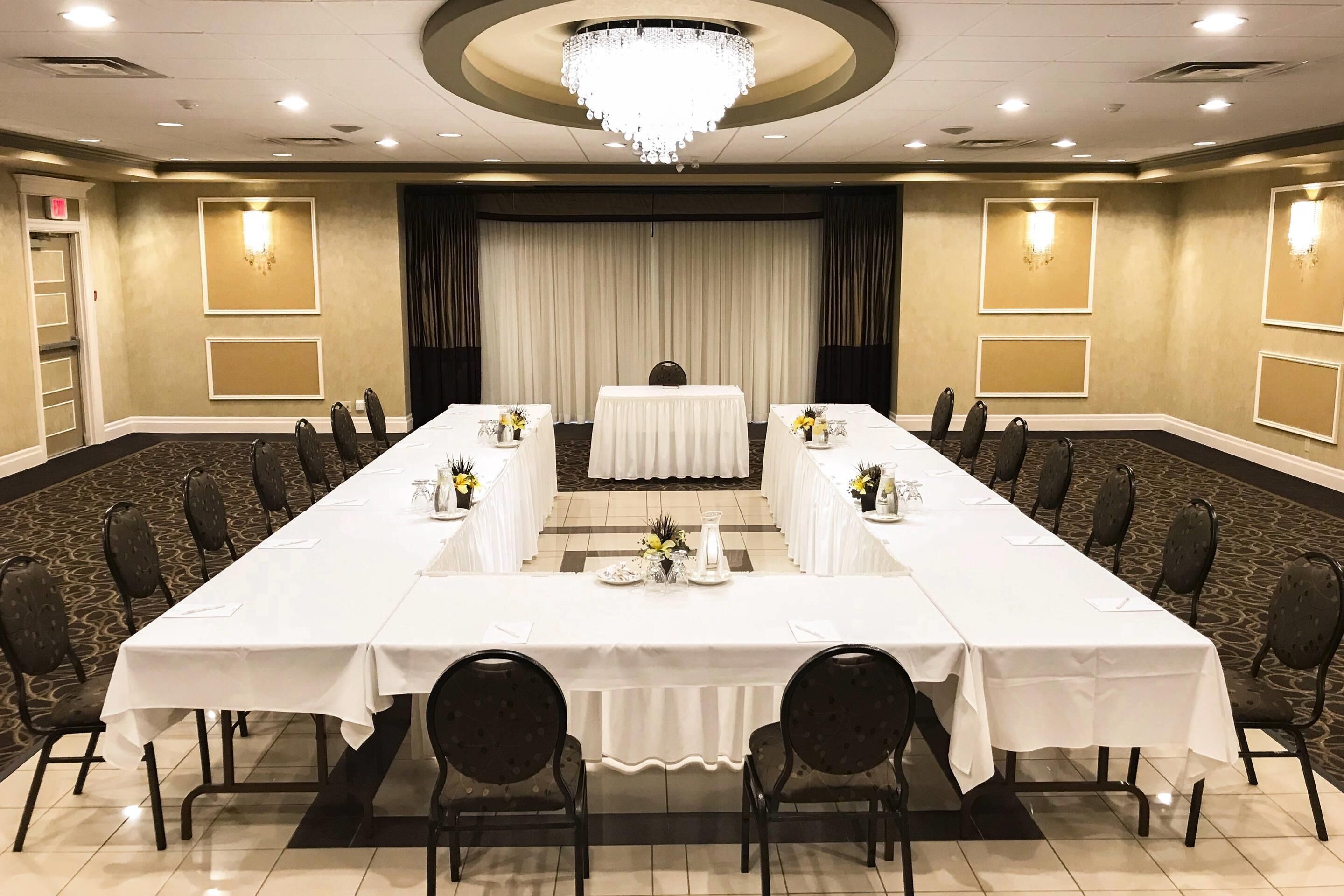 Un salón de conferencias con una larga mesa, sillas y una araña.