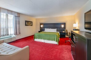 A hotel room with a bed, a desk, a chair, a television, and a window with curtains. - Rodeway Inn Festival (Stratford)
