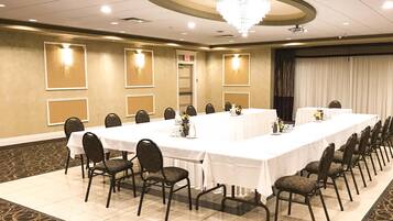 Un salón de conferencias con una mesa larga, sillas y apliques en la pared.