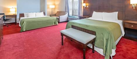 A hotel room with two beds, a desk, a chair, and a bench.