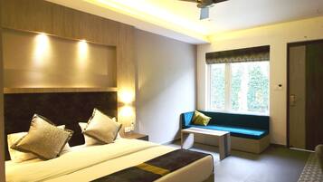 A bedroom with a bed, bedside tables, a ceiling fan, a window with a view, and a door.