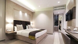 Una habitación de hotel moderna con una cama grande, una mesita de noche y un televisor montado en la pared.