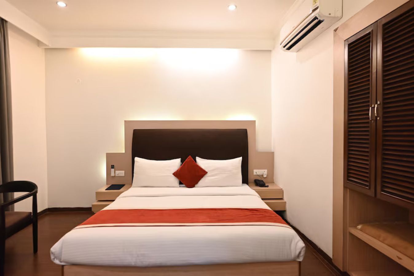 Une chambre d’hôtel comprenant un lit, des tables de chevet, un appareil de climatisation et une armoire.