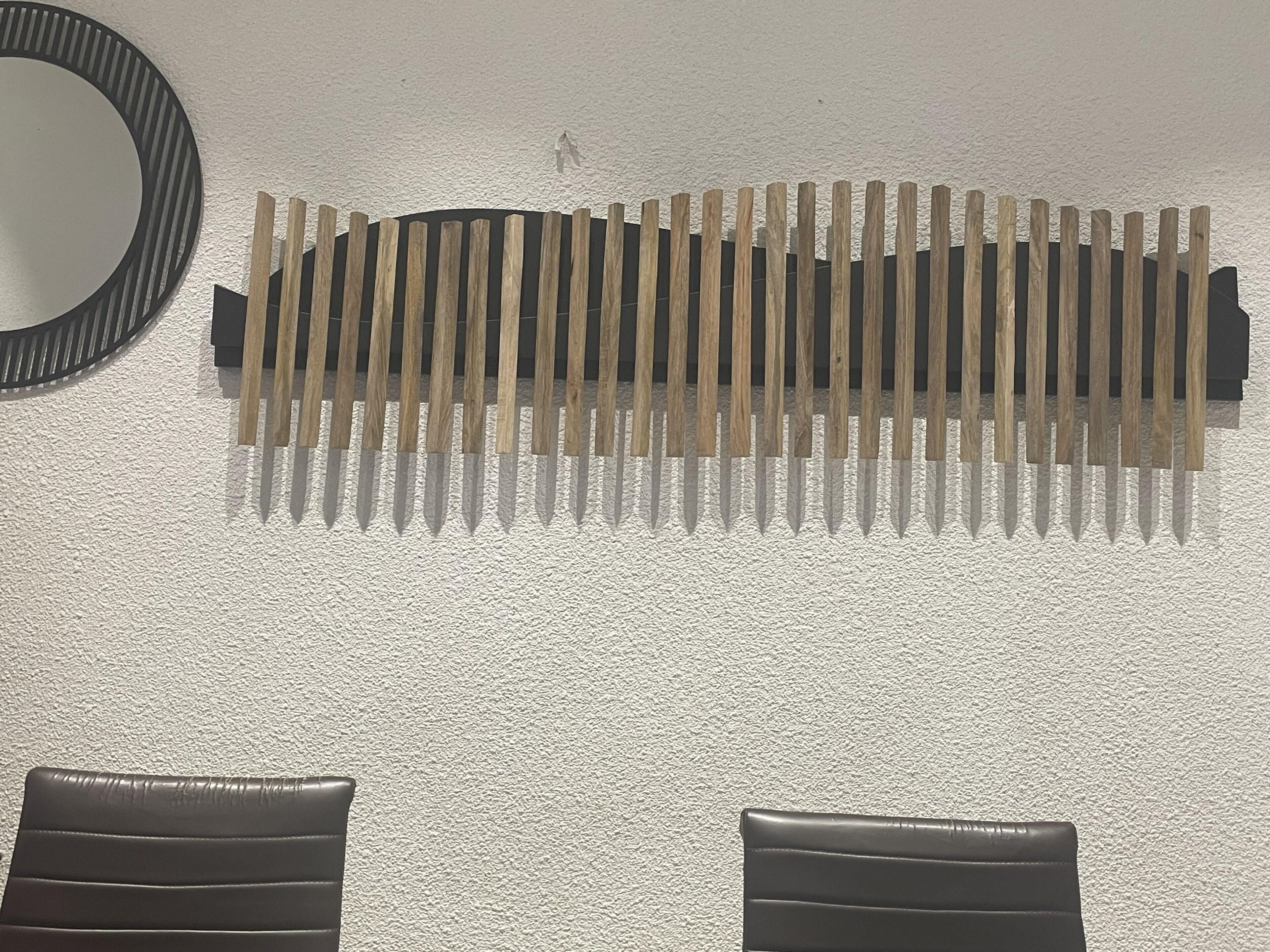 Una pared de superficie texturizada, un espejo circular y dos sillones de cuero negro.