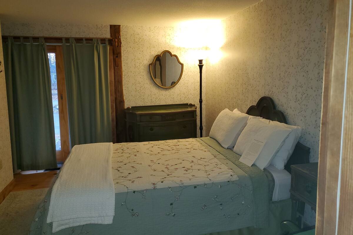 Une chambre à coucher avec un lit, une commode, un miroir et une table de chevet.