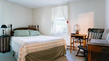 A bedroom with a bed, a desk, a chair, and a lamp.