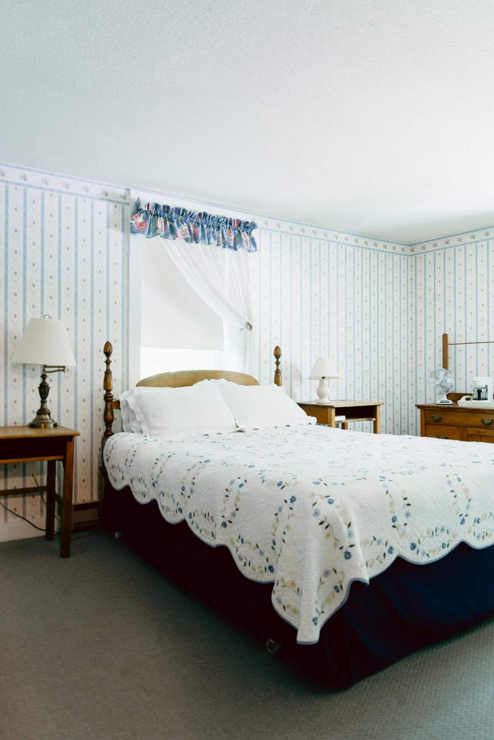 A neatly arranged bedroom with a bed, bedside tables, and a nightstand.