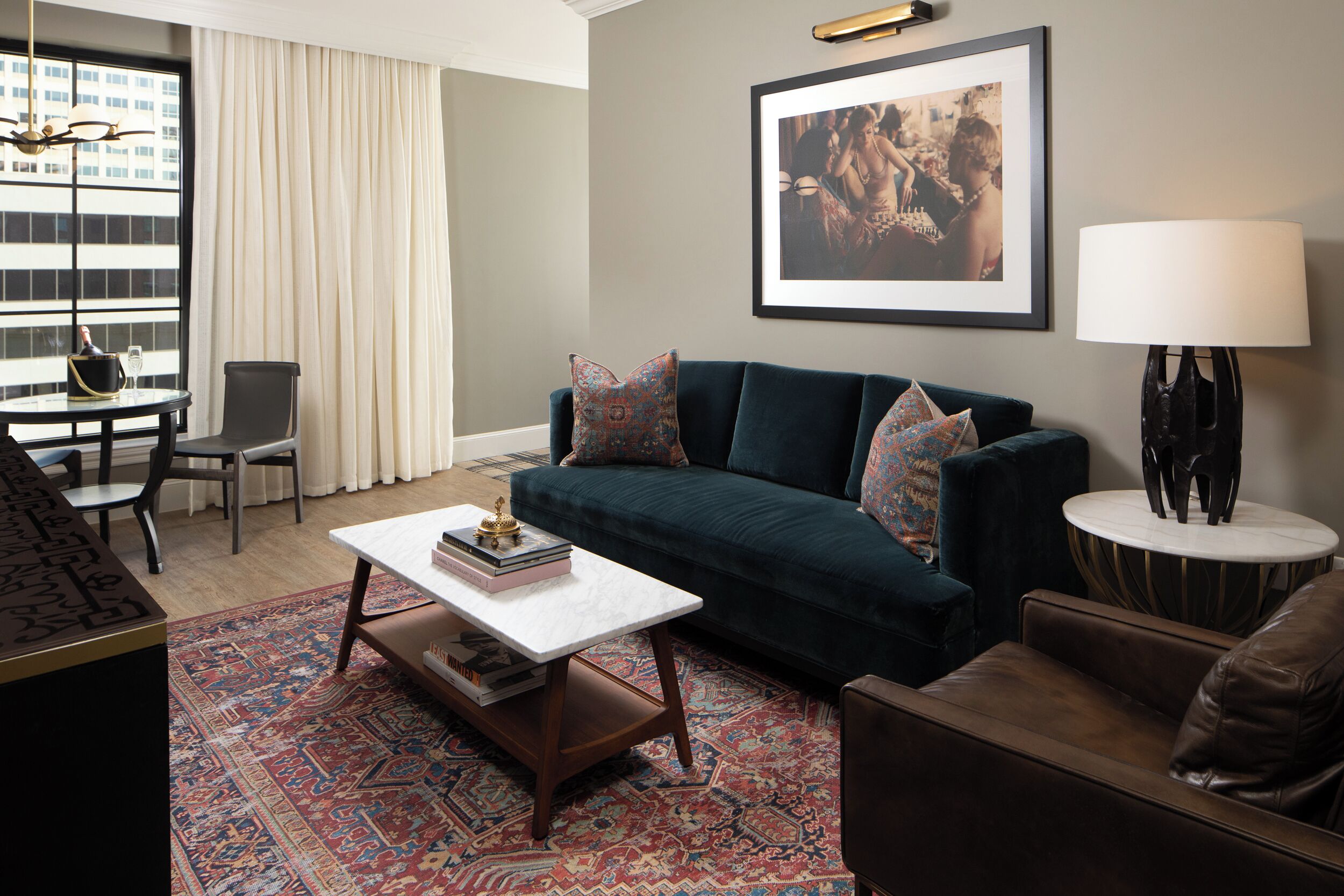 A living room with a dark green sofa, a white coffee table, a patterned rug, a framed picture on the wall, and a lamp on a side table.