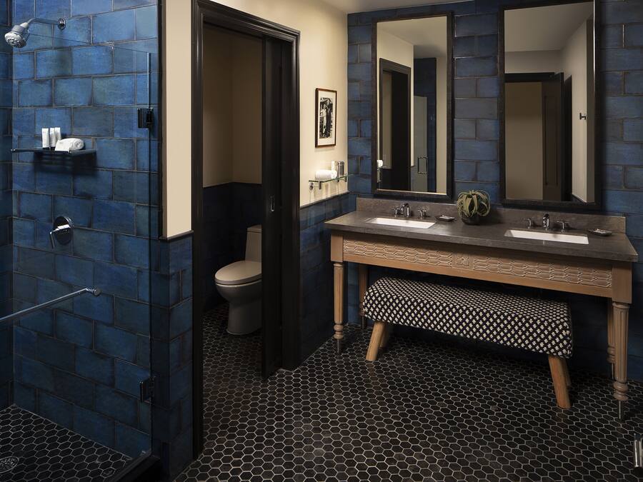 A bathroom with a shower, toilet, and a vanity with two sinks and a large mirror.