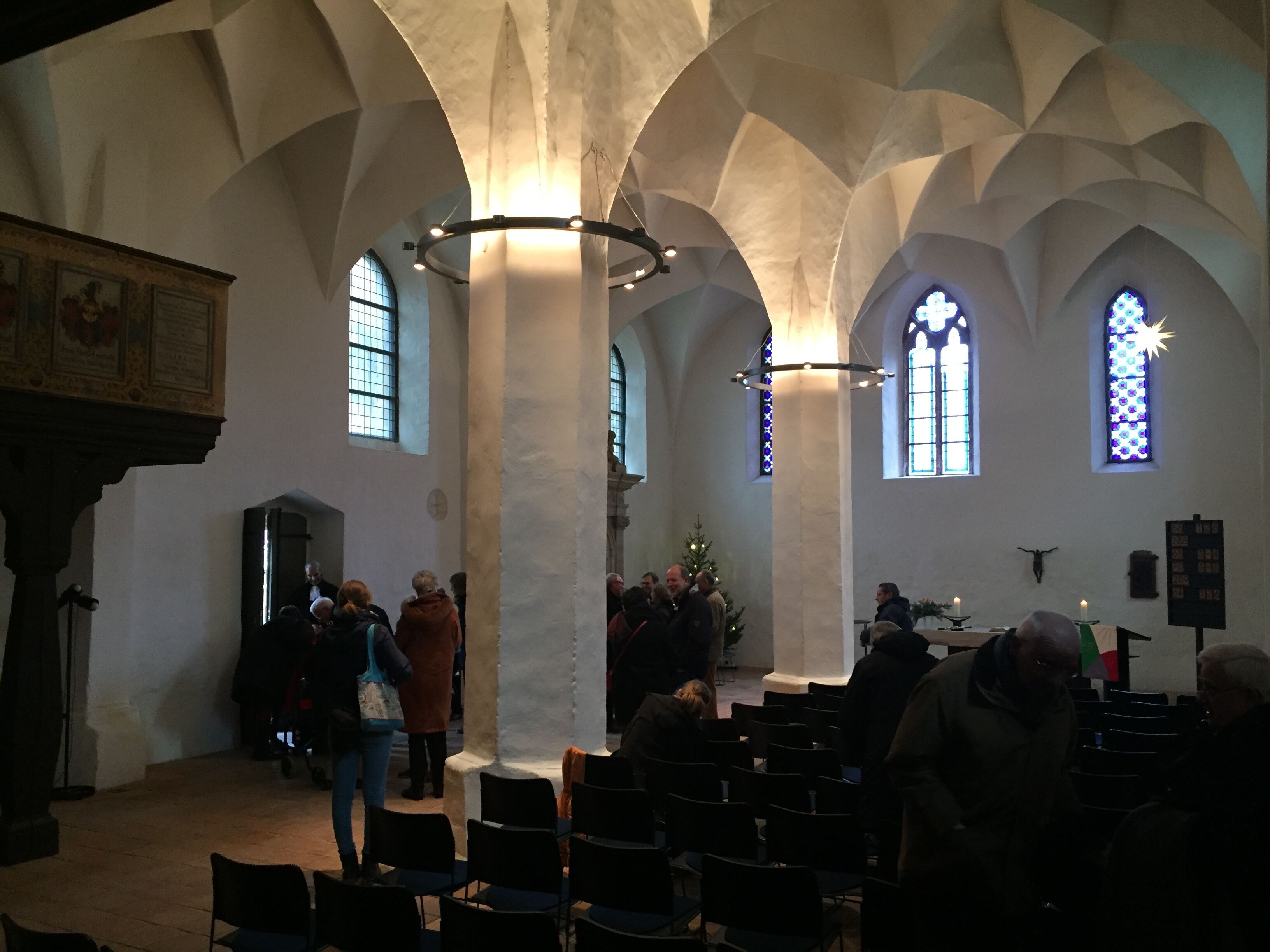 A church interior with high arched ceilings, pews, and a central aisle.