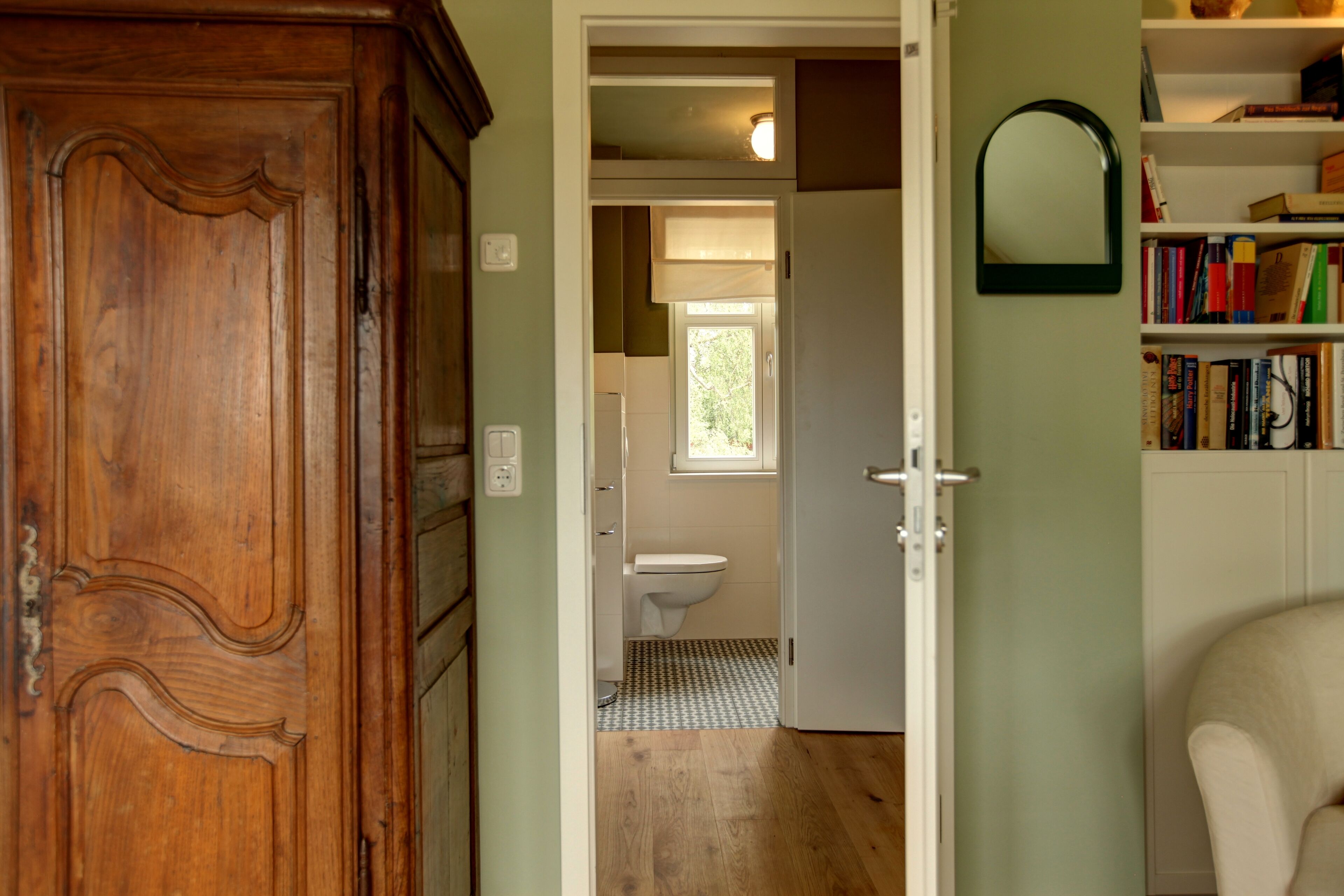 A wooden door leading to a bathroom with a toilet and a window.