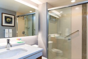 A modern bathroom with a glass-enclosed shower, a white sink with a speckled countertop, and a framed artwork on the wall. - Hyatt Place Flint / Grand Blanc (Flint)