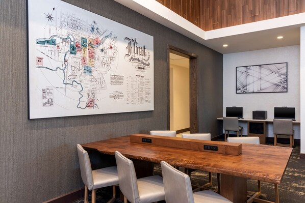 Une salle de conférence avec une grande carte accrochée au mur, une table en bois et plusieurs chaises.