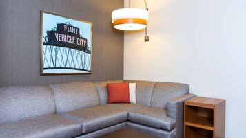Een moderne woonkamer met een grijze modulaire bank, een houten bijzettafeltje en een lijst met een foto van een brug.