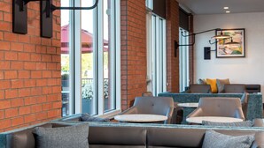 A modern indoor seating area with brick walls, large windows, and contemporary furniture. - Hyatt Place Flint / Grand Blanc (Flint)