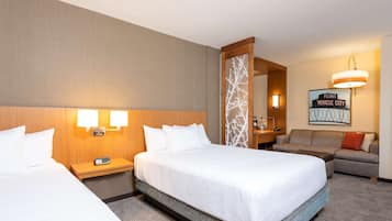 A hotel room with two beds, a sofa, a desk, and a mirror.