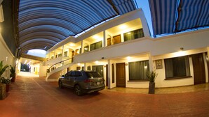 A hotel with a covered walkway, a parked car, and a staircase leading to the upper floor. - Hotel Ricarlo (Iguala de la Independencia)