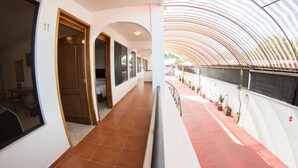 A corridor with a tiled floor, wooden doors, and a red carpeted area with potted plants. - Hotel Ricarlo (Iguala de la Independencia)