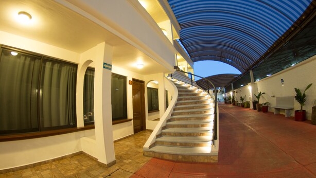 A hotel corridor with a curved staircase, a covered walkway, and potted plants. - Hotel Ricarlo (Iguala de la Independencia)