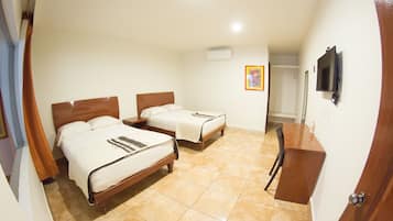 Habitación de hotel con dos camas, un escritorio, una silla y un televisor en la pared.