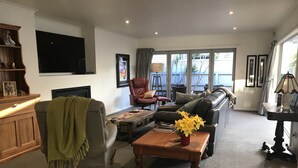 Un salon comprenant un canapé, un fauteuil, une table basse et un téléviseur fixé au mur.