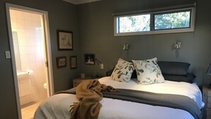 Une chambre à coucher avec un lit, une fenêtre, une table de chevet et une lampe fixée au mur.