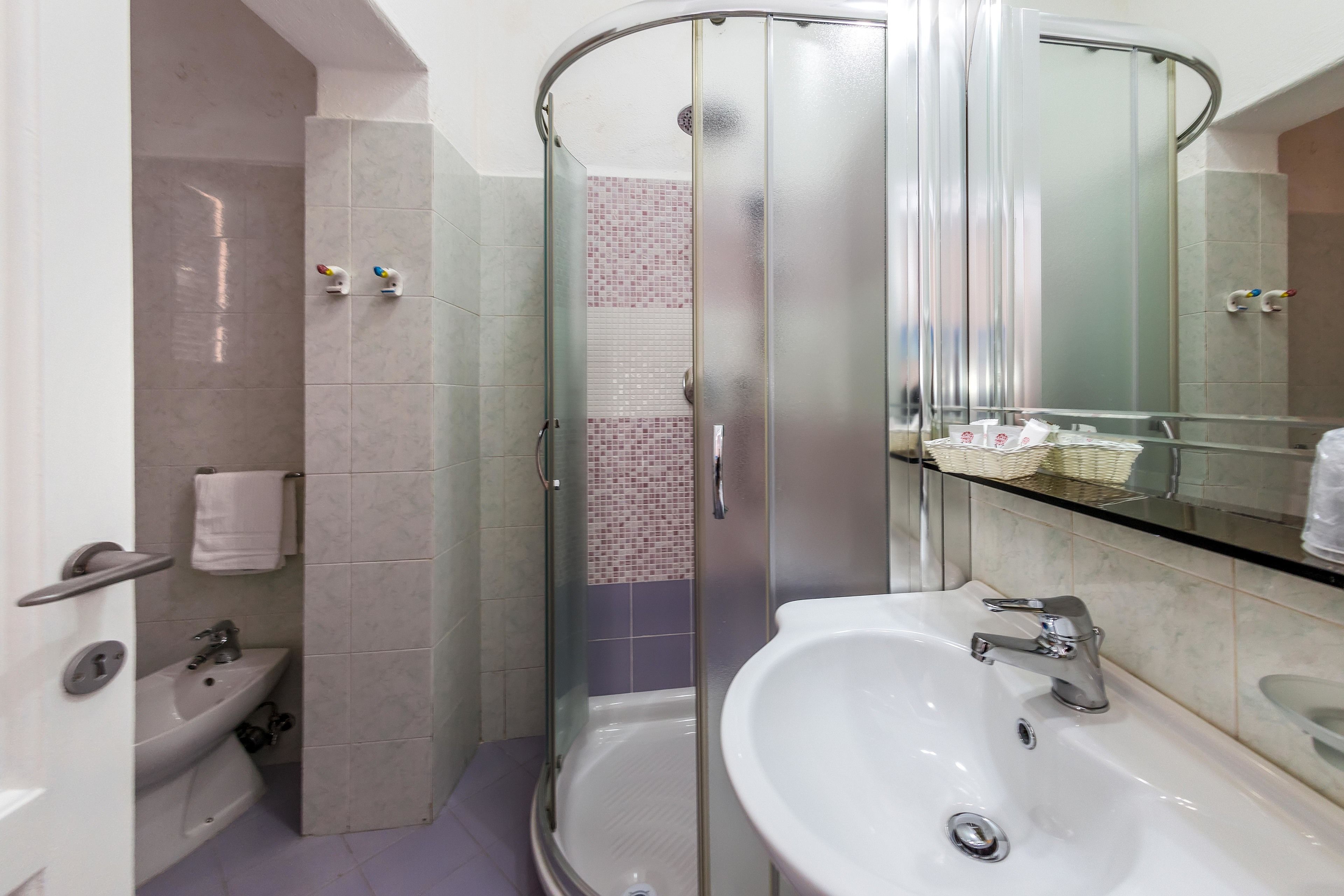 A modern bathroom with a glass-enclosed shower, a sink with a mirror, and a toilet.