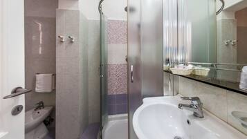 A modern bathroom with a glass-enclosed shower, a sink with a mirror, and a toilet.