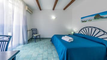 A room with a bed, a chair, a table, and a painting on the wall.