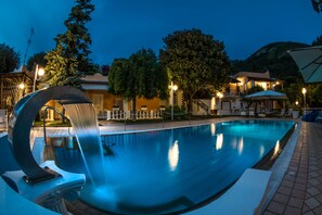 A swimming pool with a modern design, surrounded by outdoor seating and a building in the background. - Ischia Dream Sunset (Forio)