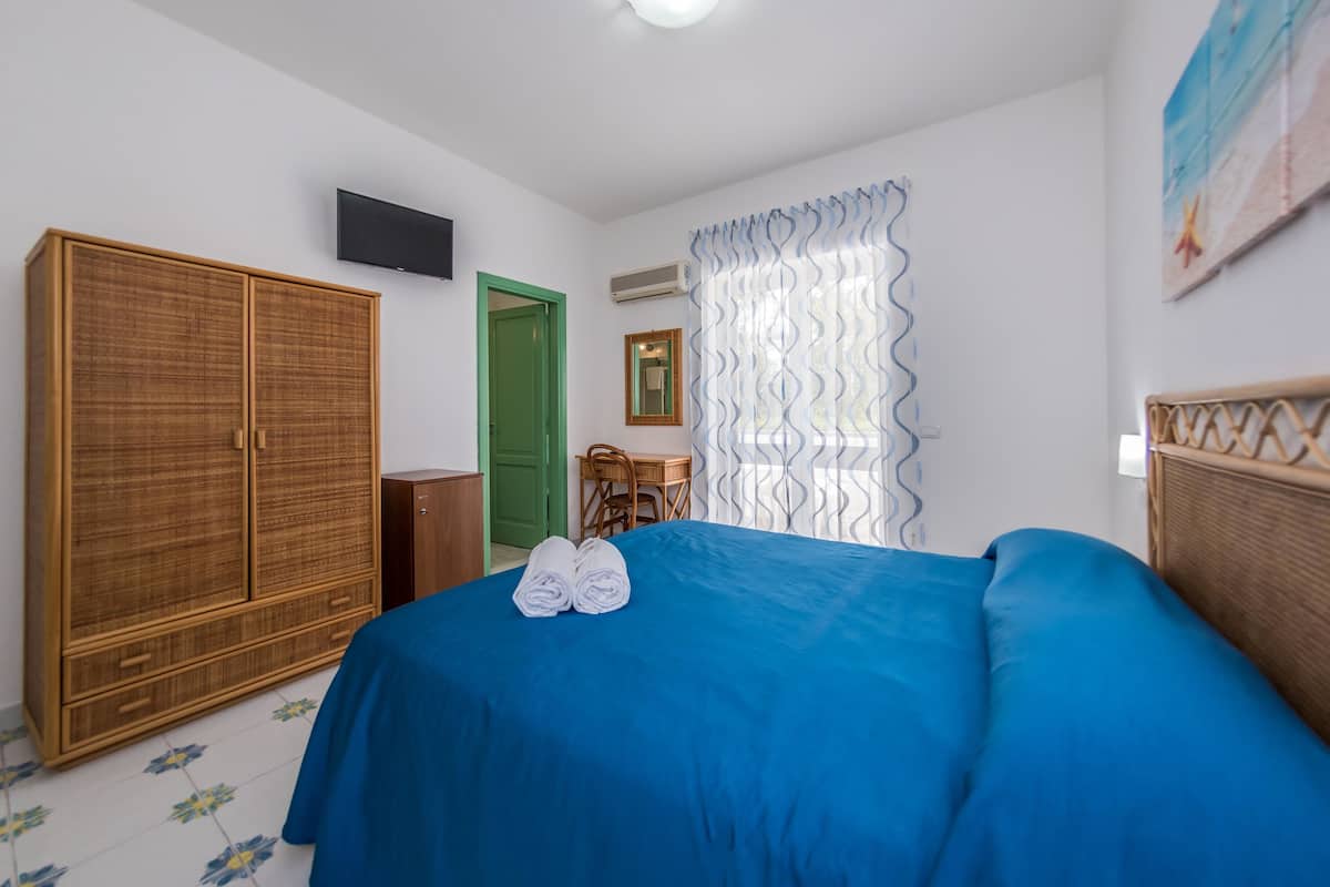 A bedroom with a bed, a wardrobe, a desk, and a chair.