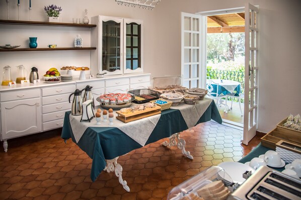 A breakfast buffet setup with various food items and a view of the outdoor patio.