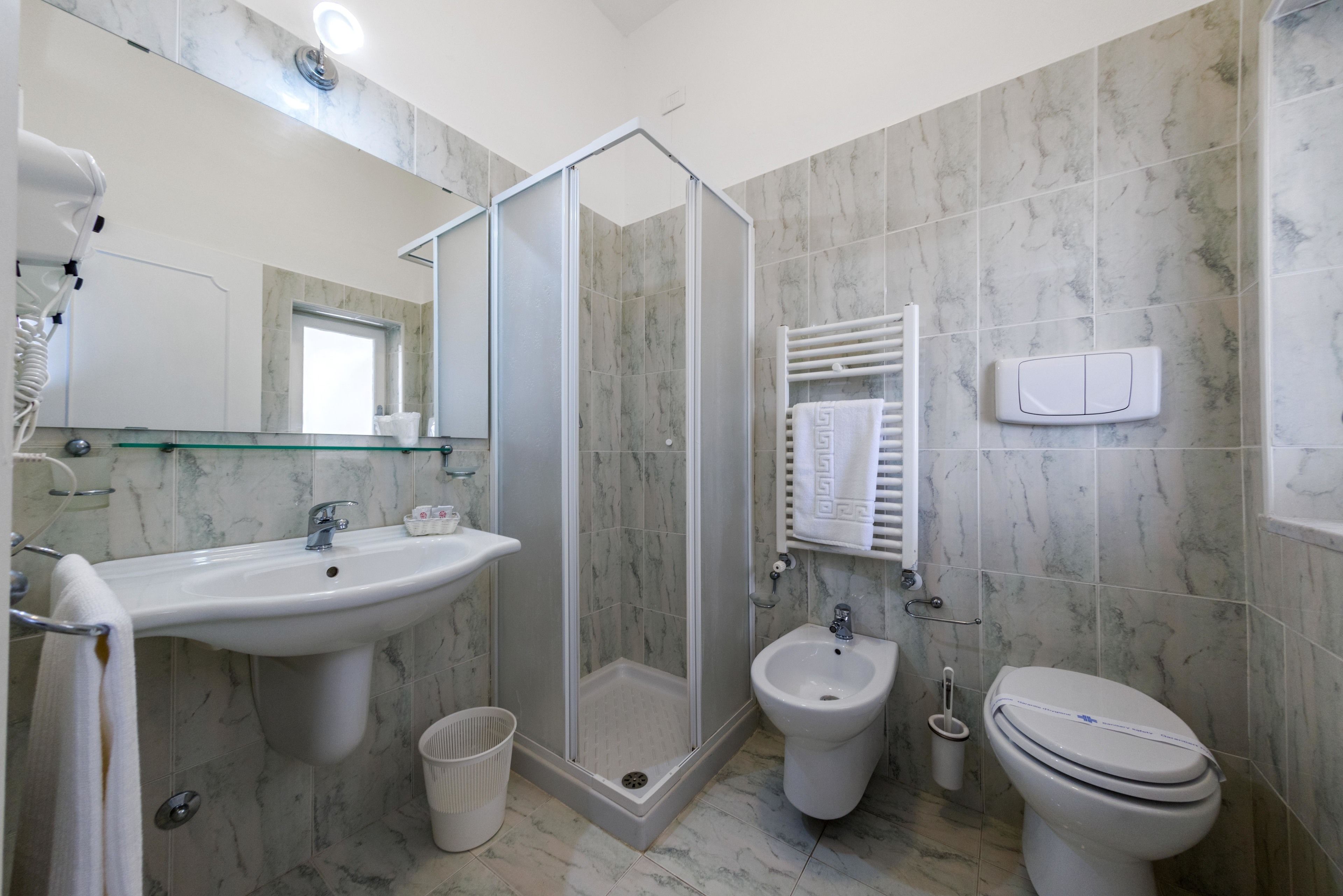 Un bagno moderno con doccia vetro, lavandino, bidet e WC.