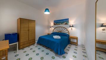 A bedroom with a bed, a wardrobe, a desk, and a chair.