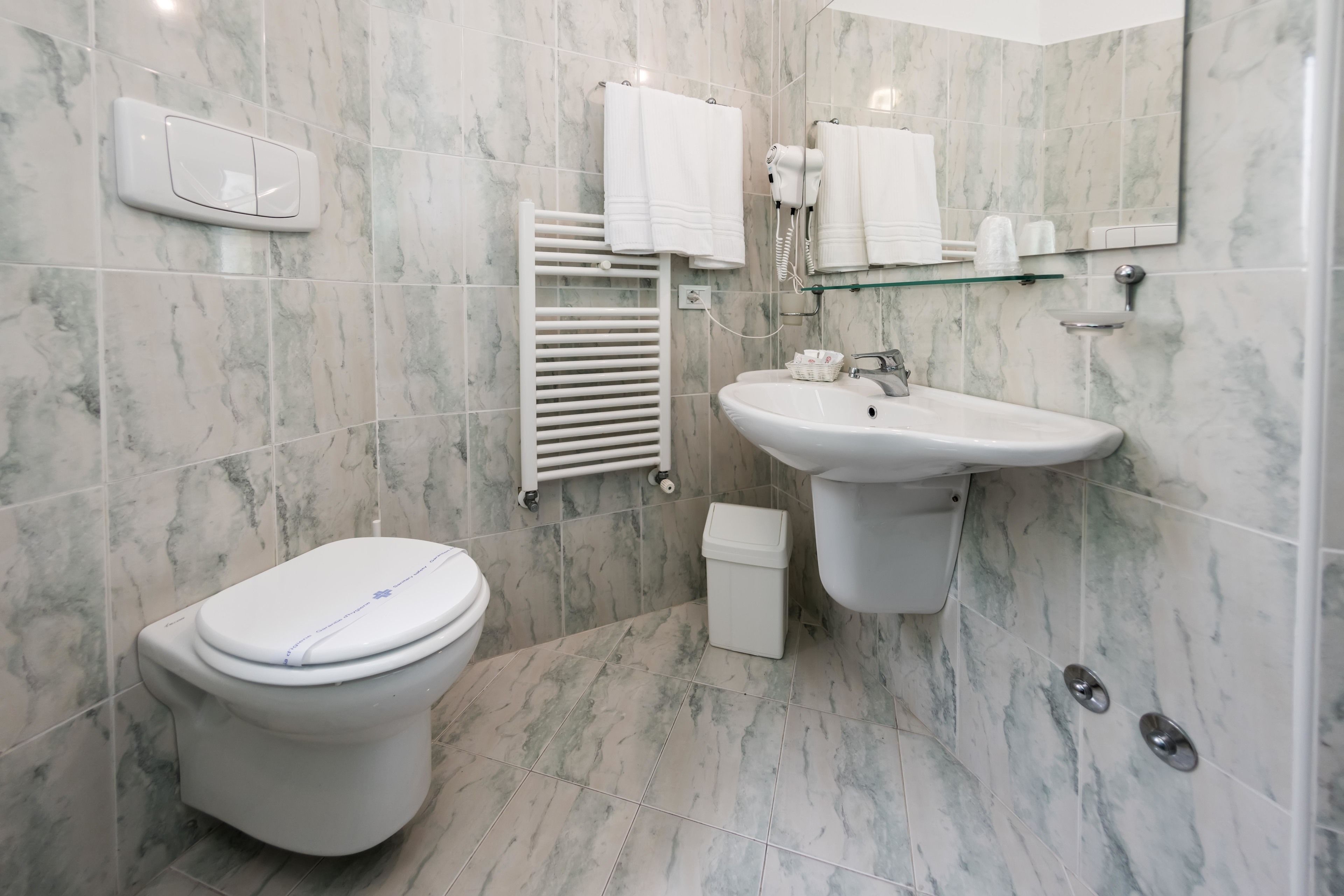 Casa de banho moderna com sanita, lavatório e suporte para toalhas.