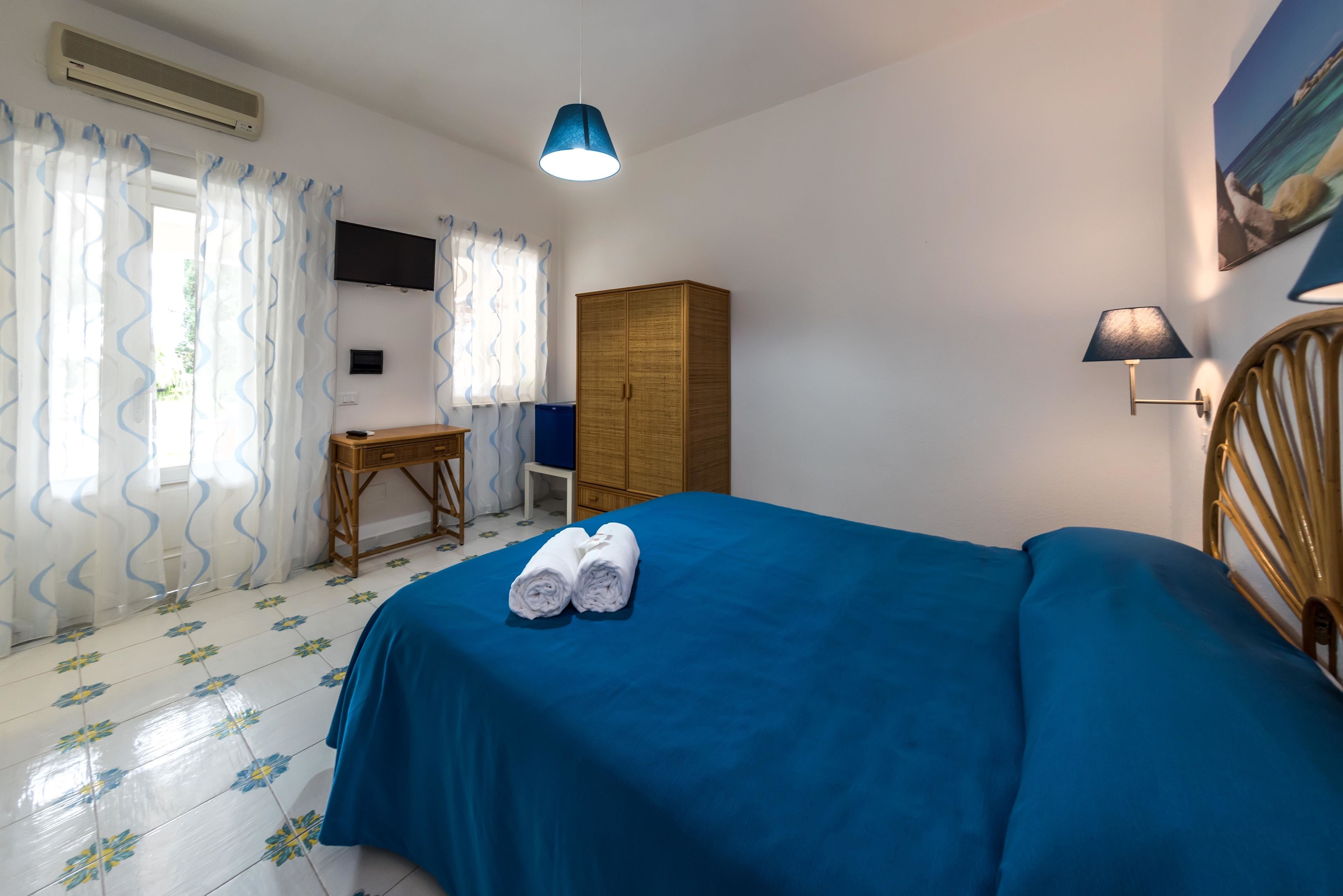 Un dormitorio con cama, escritorio, armario y televisor en la pared.