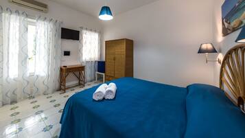Un dormitorio con cama, escritorio, armario y televisor en la pared.