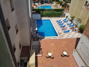 Un área de piscina en la azotea con sillones de descanso y una piscina más pequeña.