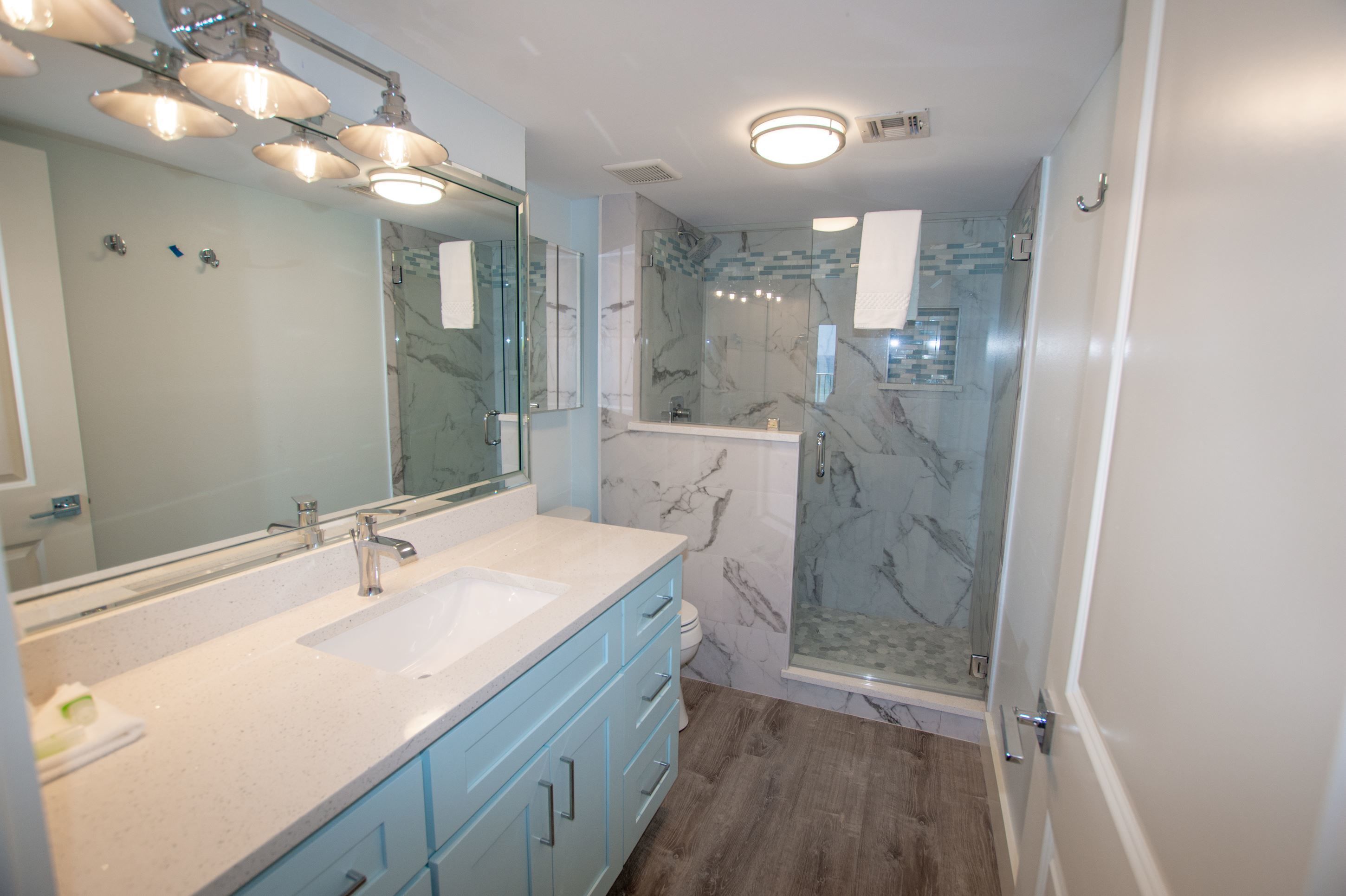 Une salle de bain moderne avec deux vasques, une douche en verre et des murs en marbre.